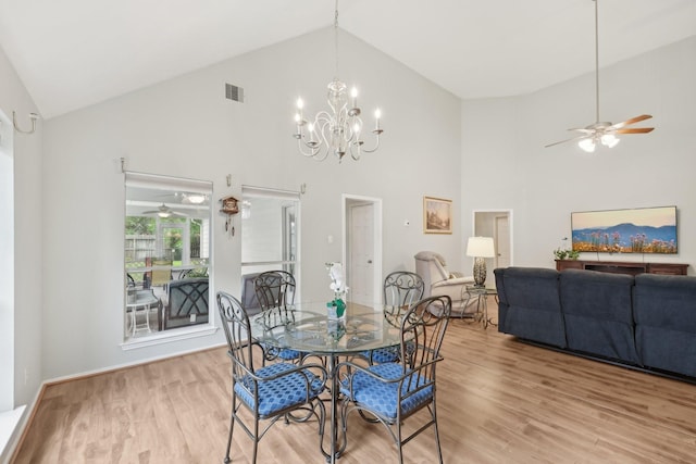 dining area featuring high vaulted ceiling, a ceiling fan, light wood-style floors, a chandelier, and baseboards