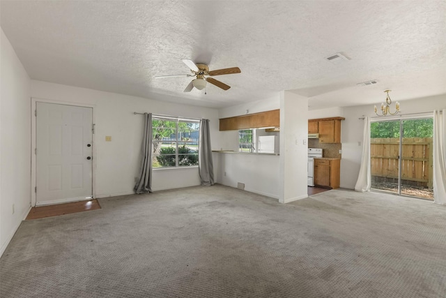 217 Lazy Ln, Conroe, TX 77301 - unfurnished living room with a chandelier, a textured ceiling, a ceiling fan, light carpet, and baseboards