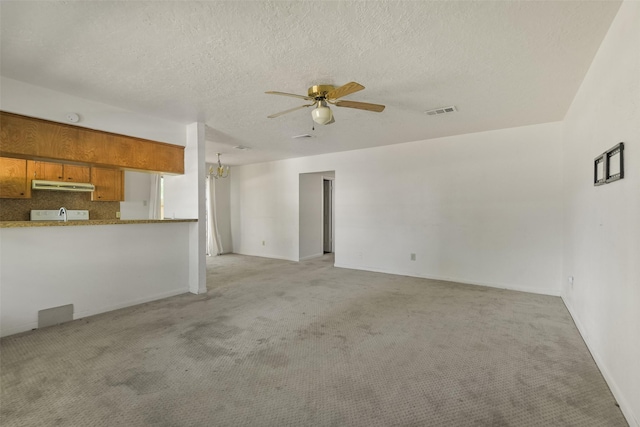 217 Lazy Ln, Conroe, TX 77301 - unfurnished living room with light colored carpet, a ceiling fan, and a textured ceiling