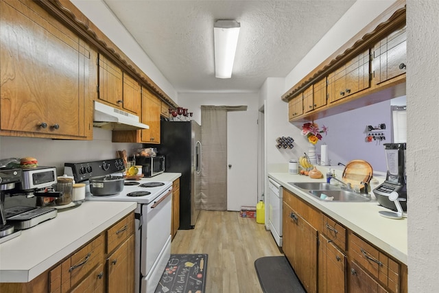 217 Lazy Ln, Conroe, TX 77301 - kitchen featuring appliances with stainless steel finishes, under cabinet range hood, a sink, light wood finished floors, and light countertops
