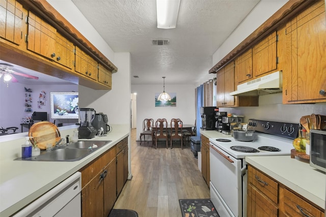 217 Lazy Ln, Conroe, TX 77301 - kitchen with white appliances, under cabinet range hood, light countertops, brown cabinetry, and a textured ceiling