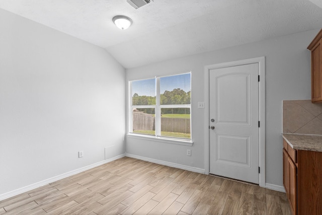 unfurnished dining area with light wood-style flooring, lofted ceiling, and baseboards
