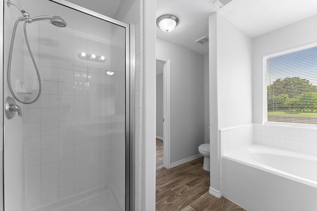 full bathroom featuring a stall shower, wood finished floors, a bath, toilet, and baseboards