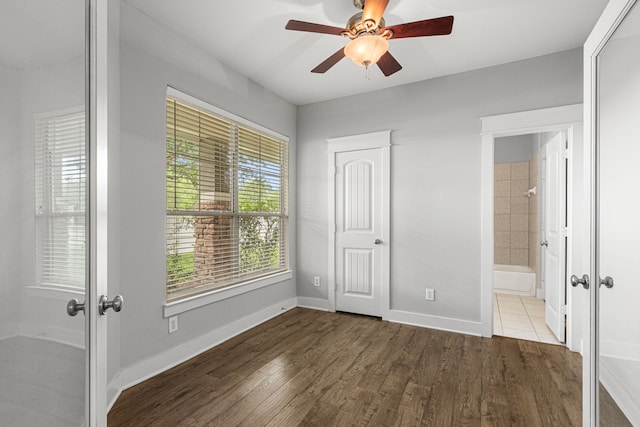 unfurnished bedroom with wood finished floors, baseboards, ensuite bath, and french doors