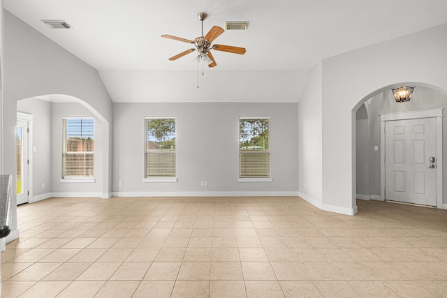 spare room with lofted ceiling, arched walkways, light tile patterned floors, plenty of natural light, and ceiling fan