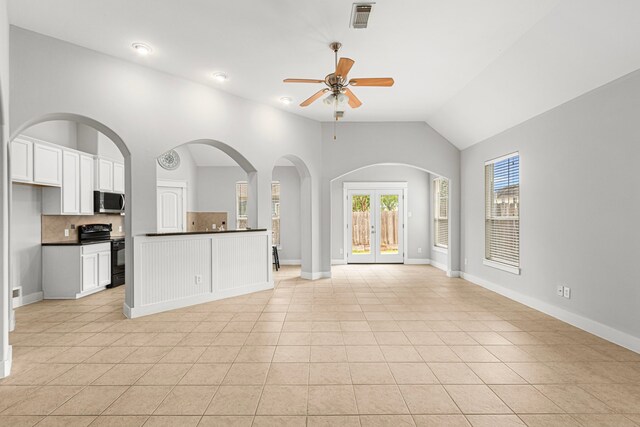 unfurnished living room featuring ceiling fan, light tile patterned flooring, lofted ceiling, and baseboards