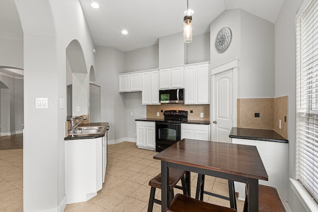 kitchen featuring black electric range, stainless steel microwave, arched walkways, a sink, and high vaulted ceiling