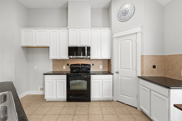 kitchen with stainless steel microwave, black electric range, white cabinetry, and dark countertops