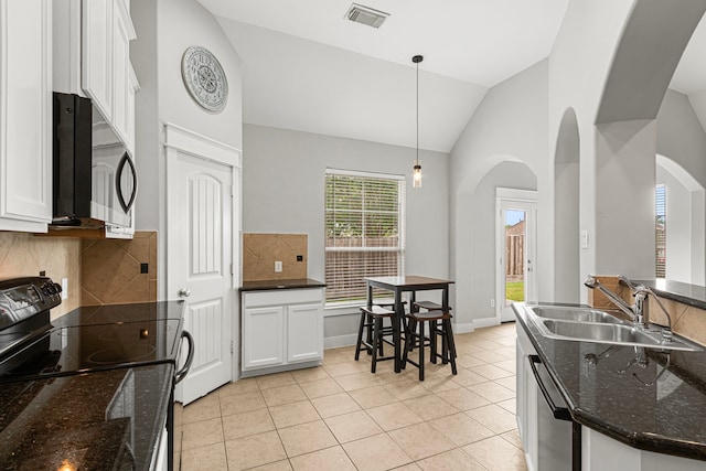 kitchen with a sink, arched walkways, stainless steel dishwasher, plenty of natural light, and high vaulted ceiling