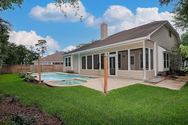 rear view of house featuring an in-ground hot tub, a chimney, a sunroom, and a patio