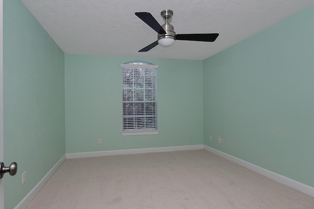 carpeted empty room with ceiling fan, a textured ceiling, and baseboards