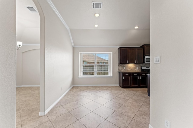 2043 Plum Rose Ln, Richmond, TX 77469 - kitchen with stainless steel microwave, dark brown cabinetry, ornamental molding, lofted ceiling, and light tile patterned floors