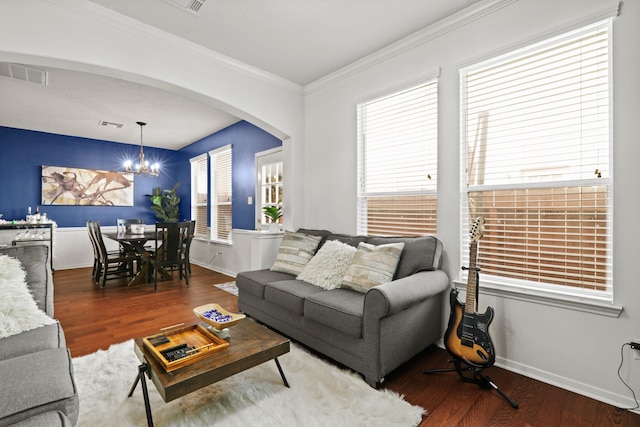 living area with a chandelier, wood finished floors, arched walkways, crown molding, and baseboards