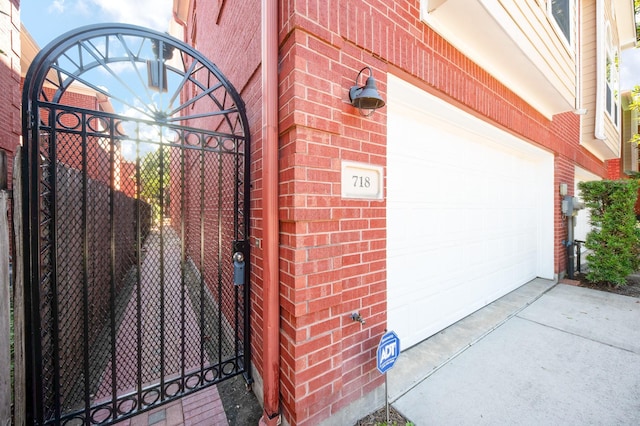 718 Roy St, Houston, TX 77007 - view of exterior entry with driveway, brick siding, a garage, and a gate