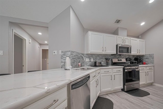 19942 Mountain Dale Dr, Cypress, TX 77433 - kitchen featuring appliances with stainless steel finishes, a sink, backsplash, light stone countertops, and light wood finished floors