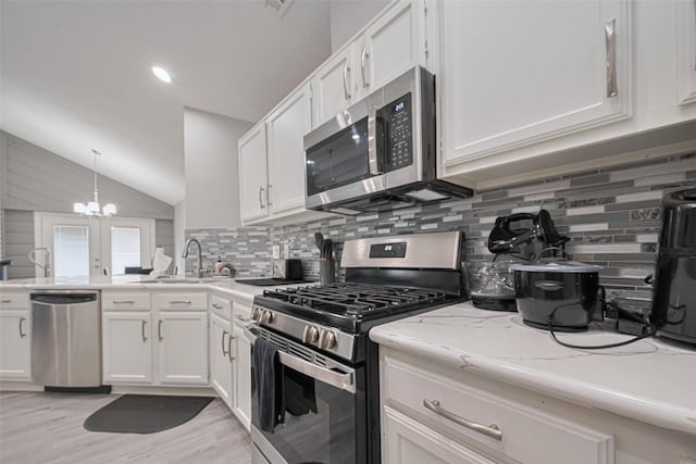 19942 Mountain Dale Dr, Cypress, TX 77433 - kitchen with appliances with stainless steel finishes, a sink, white cabinets, vaulted ceiling, and backsplash