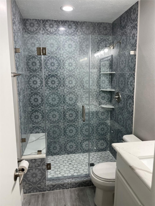 19942 Mountain Dale Dr, Cypress, TX 77433 - bathroom featuring wood finished floors, toilet, a stall shower, vanity, and a textured ceiling