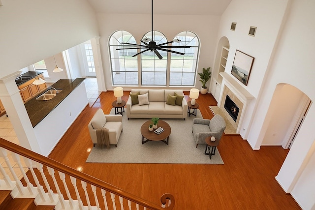 6334 Goodlowe Park, Sugar Land, TX 77479 - living room featuring wood finished floors, plenty of natural light, high vaulted ceiling, a warm lit fireplace, and arched walkways