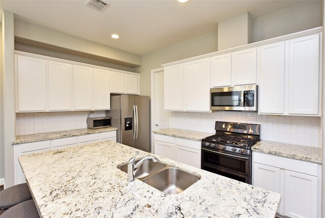 5502 Camaguey St, Houston, TX 77023 - kitchen with stainless steel appliances, a sink, white cabinetry, tasteful backsplash, and recessed lighting