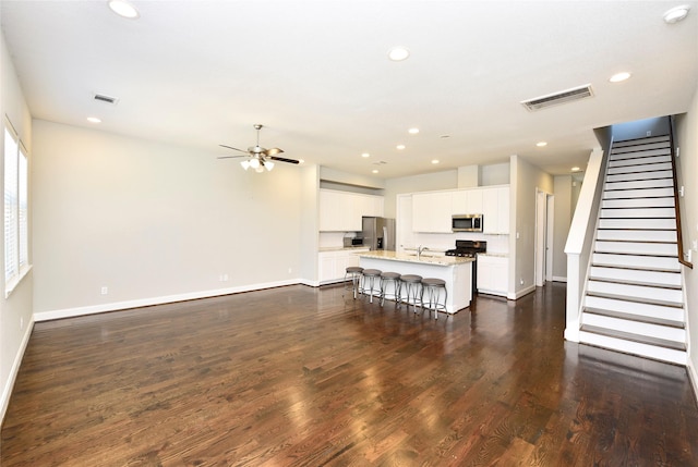 5502 Camaguey St, Houston, TX 77023 - living area with baseboards, recessed lighting, dark wood-type flooring, a ceiling fan, and stairs
