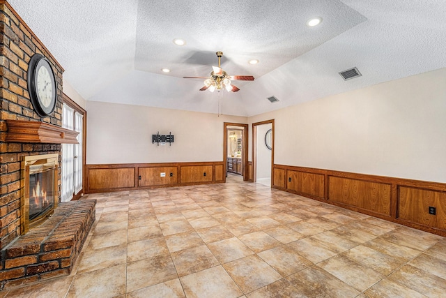 1618 Monroe Dr, Deer Park, TX 77536 - unfurnished living room featuring a wainscoted wall, a textured ceiling, a fireplace, a ceiling fan, and lofted ceiling