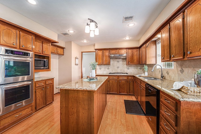 1618 Monroe Dr, Deer Park, TX 77536 - kitchen with a sink, stainless steel appliances, brown cabinetry, light wood finished floors, and under cabinet range hood
