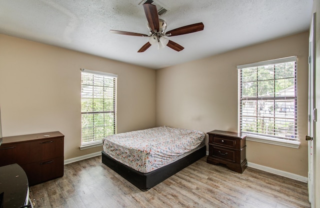 2915 Quailwood St, Houston, TX 77014 - bedroom featuring light wood finished floors, baseboards, a textured ceiling, and ceiling fan