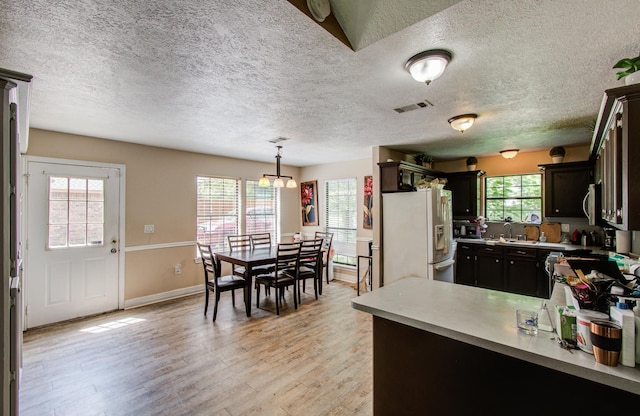 2915 Quailwood St, Houston, TX 77014 - kitchen with white refrigerator with ice dispenser, a textured ceiling, light countertops, light wood-style floors, and hanging light fixtures