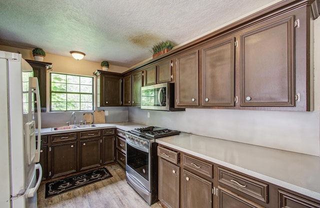 2915 Quailwood St, Houston, TX 77014 - kitchen featuring appliances with stainless steel finishes, a sink, light wood-style flooring, light countertops, and a textured ceiling