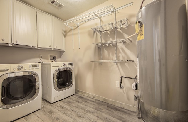 2915 Quailwood St, Houston, TX 77014 - clothes washing area with cabinet space, separate washer and dryer, light wood-type flooring, water heater, and baseboards
