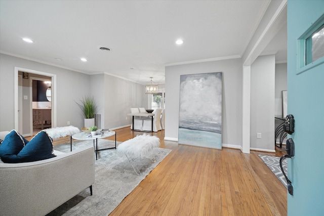 living area featuring wood finished floors, recessed lighting, ornamental molding, a chandelier, and baseboards