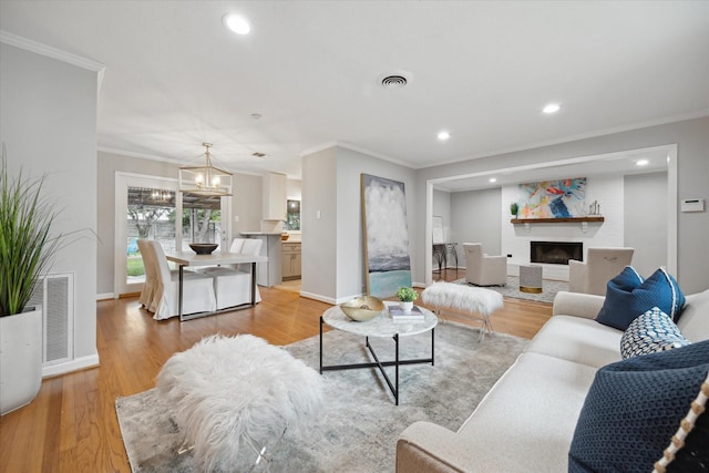 living room featuring crown molding, light wood-style flooring, recessed lighting, a chandelier, and baseboards