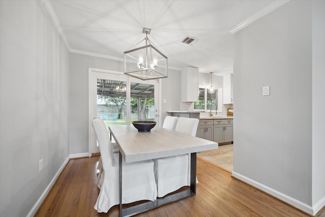 dining room featuring a chandelier, baseboards, ornamental molding, and wood finished floors