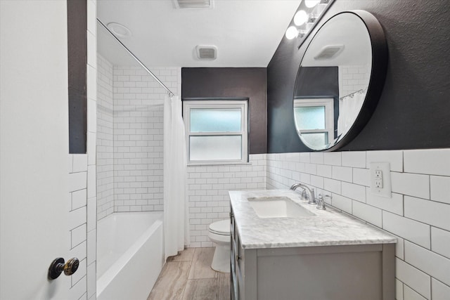 full bathroom with toilet, tile walls, vanity, and shower / bath combination with curtain