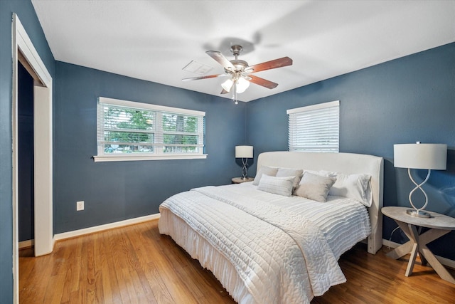 bedroom with wood finished floors, baseboards, a closet, and a ceiling fan