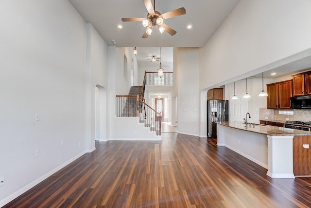 8246 Mandalay Bay Dr, Baytown, TX 77523 - kitchen with appliances with stainless steel finishes, dark wood finished floors, ceiling fan, brown cabinetry, and a towering ceiling