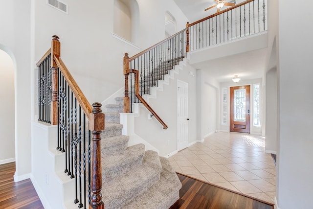 8246 Mandalay Bay Dr, Baytown, TX 77523 - stairs with arched walkways, baseboards, a towering ceiling, tile patterned floors, and ceiling fan