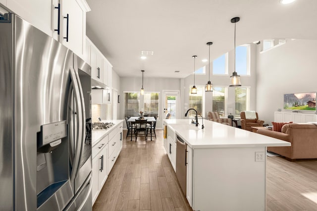 kitchen with appliances with stainless steel finishes, open floor plan, light wood-type flooring, light countertops, and recessed lighting