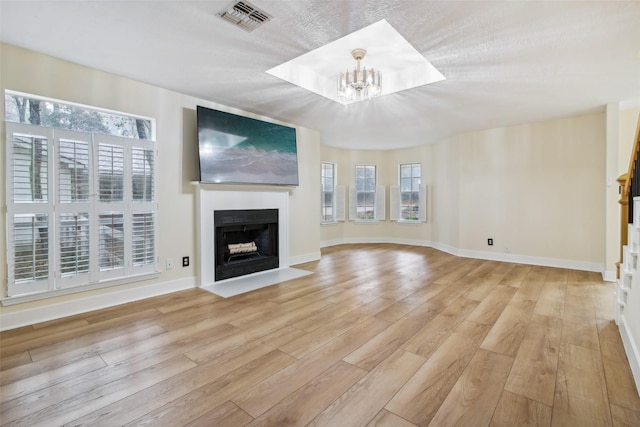 28 Stony Creek Dr, Conroe, TX 77384 - unfurnished living room featuring a chandelier, a fireplace with flush hearth, plenty of natural light, and light wood-style floors
