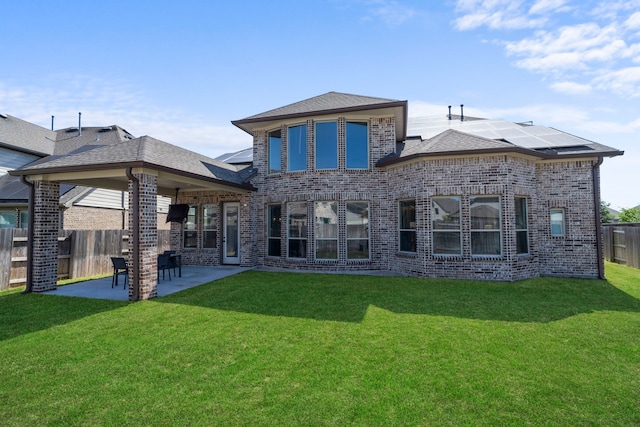 back of property with brick siding, solar panels, a patio, and a shingled roof