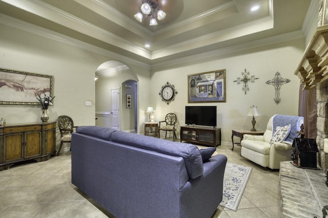 living room featuring arched walkways, light tile patterned flooring, ornamental molding, and a raised ceiling