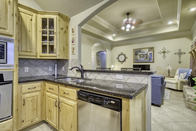 kitchen featuring appliances with stainless steel finishes, a sink, arched walkways, a peninsula, and open floor plan