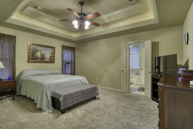 carpeted bedroom featuring a tray ceiling, crown molding, ensuite bathroom, ceiling fan, and baseboards
