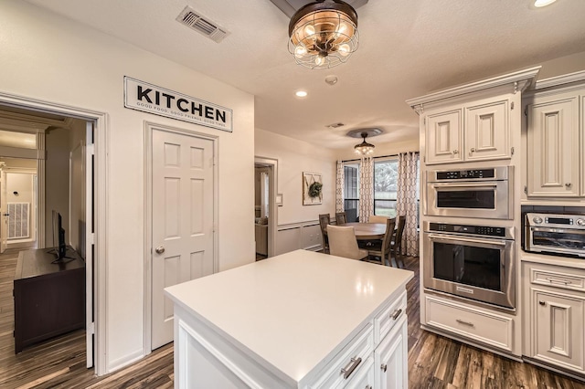 kitchen featuring double oven, dark wood-type flooring, light countertops, recessed lighting, and a chandelier