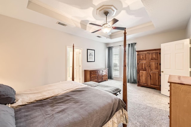 bedroom with a tray ceiling, light colored carpet, ornamental molding, and ceiling fan