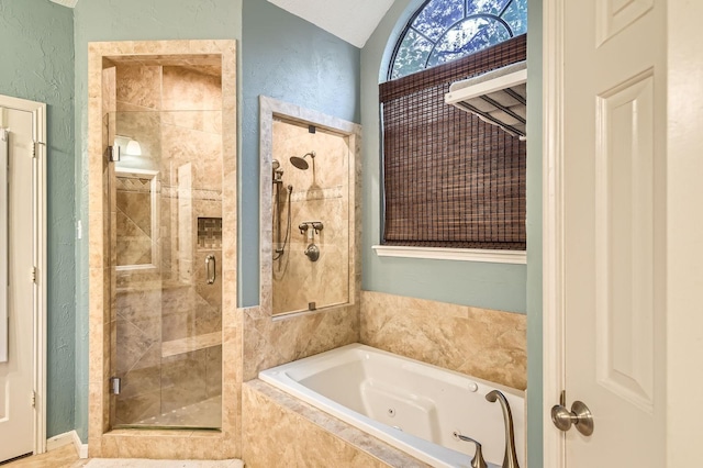 full bath featuring a stall shower, a tub with jets, vaulted ceiling, and a textured wall