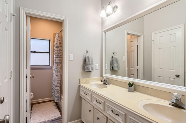 full bath with toilet, double vanity, baseboards, and curtained shower