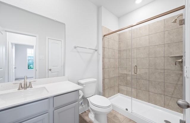 18127 Shoreline Vista Ln, Cypress, TX 77433 - full bathroom featuring a stall shower, toilet, tile patterned flooring, and vanity