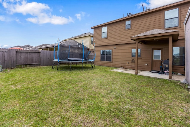 rear view of property with a trampoline and a patio