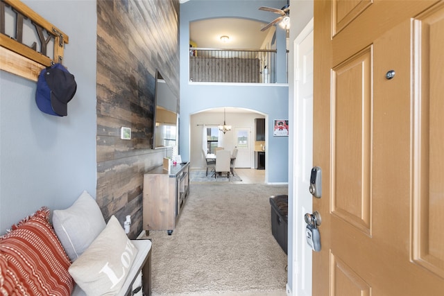 entrance foyer featuring arched walkways, carpet, wood walls, and a ceiling fan